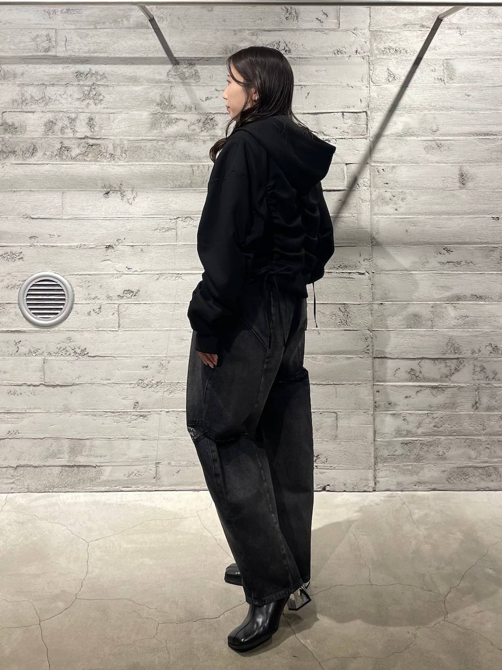 ブラック系のブーツ、ブラック系のデニムパンツ、ブラック系のパーカーを着用したレディースの冬コーディネートの2枚目の写真