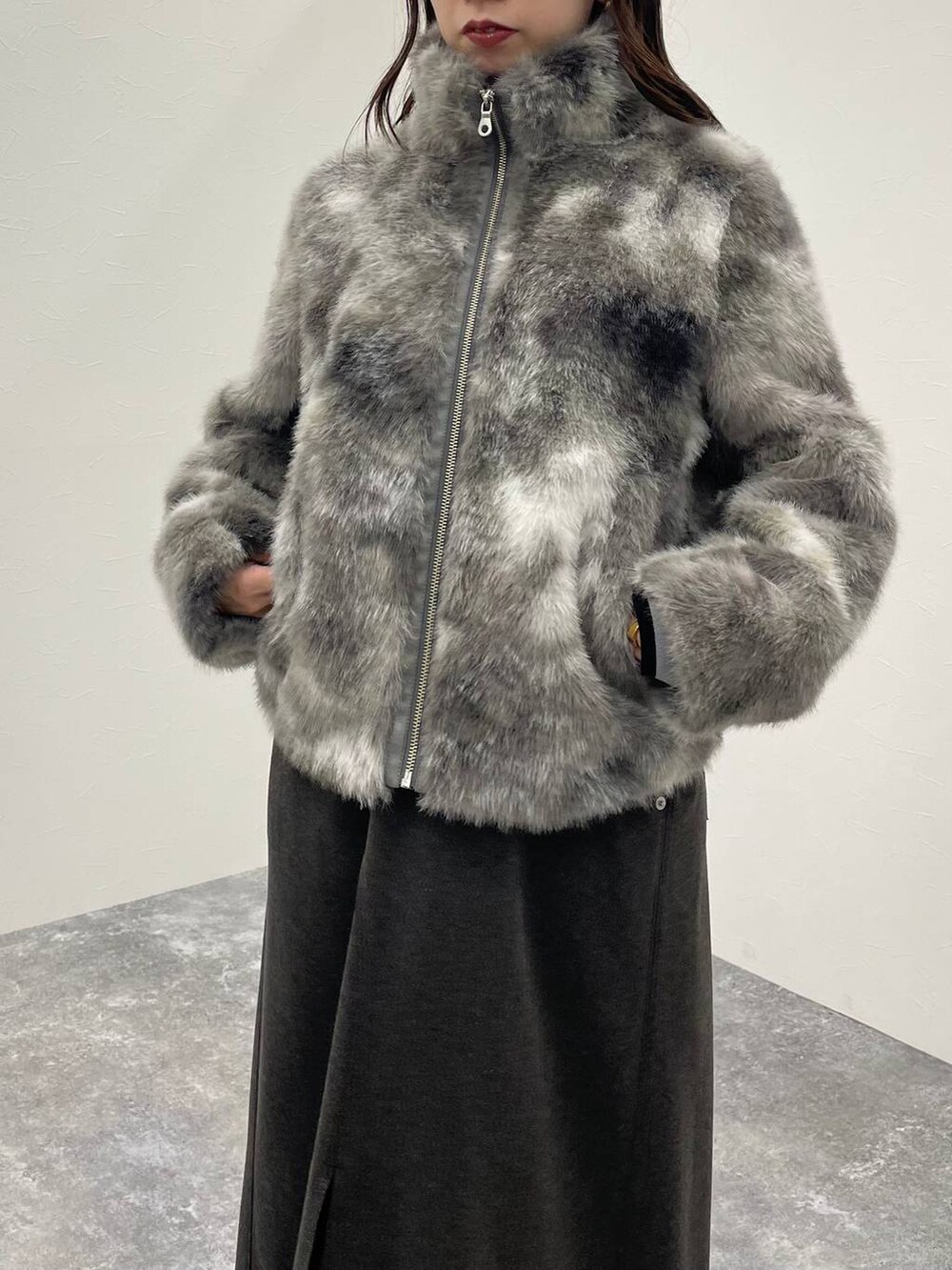 グレー系のブルゾン、ブラック系のブーツ、グレー系のスカートを着用したレディースの秋コーディネートの4枚目の写真