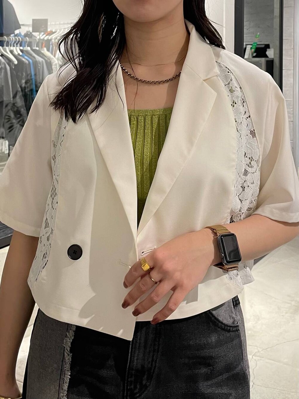 イエロー系のタンクトップ、ブラック系のデニムスカート、ホワイト系のテーラードジャケットを着用したレディースの春コーディネートの4枚目の写真