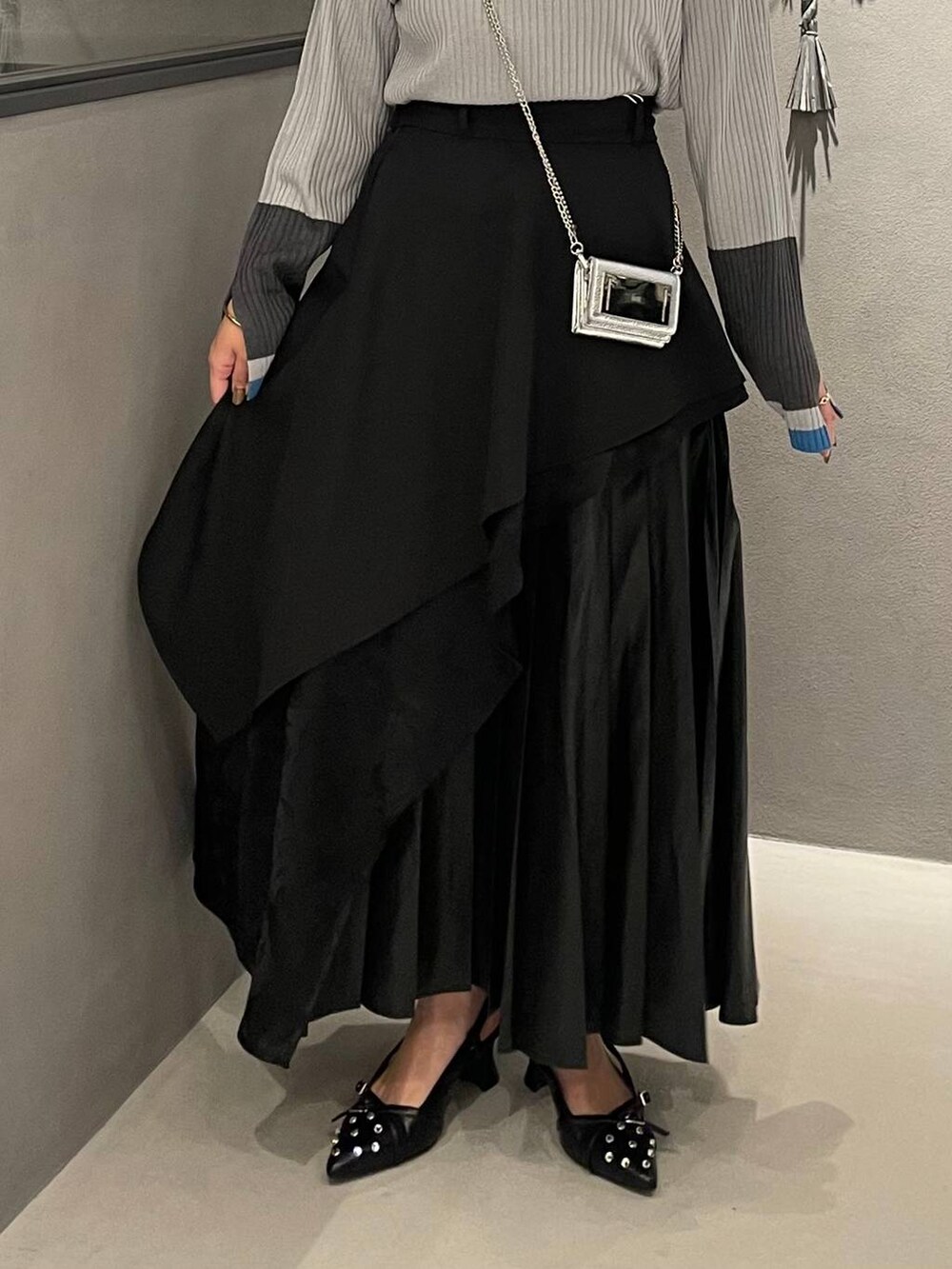 ブラック系のスカート、ブラック系のパンプス、グレー系のニット/セーターを着用したレディースの秋コーディネートの5枚目の写真