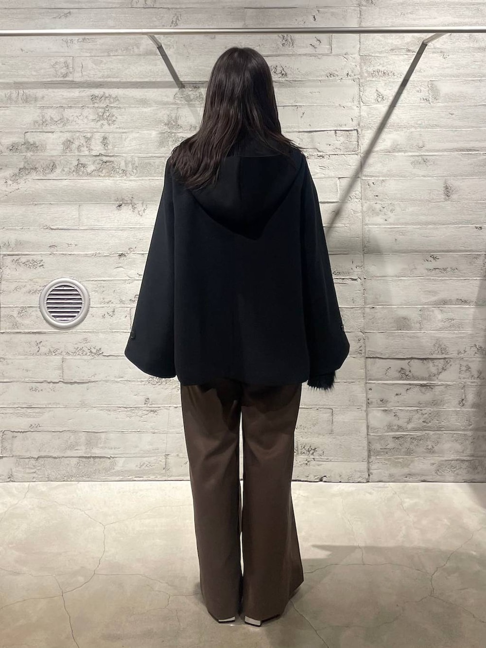 ブラック系のブーツ、ブラック系のノーカラーコート、ブラウン系のその他パンツを着用したレディースの冬コーディネートの4枚目の写真