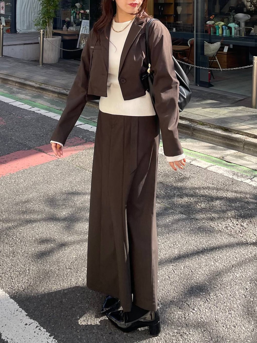 ブラック系のショルダーバッグ、ブラウン系のテーラードジャケット、ブラウン系のスカートを着用したレディースの冬コーディネートの4枚目の写真