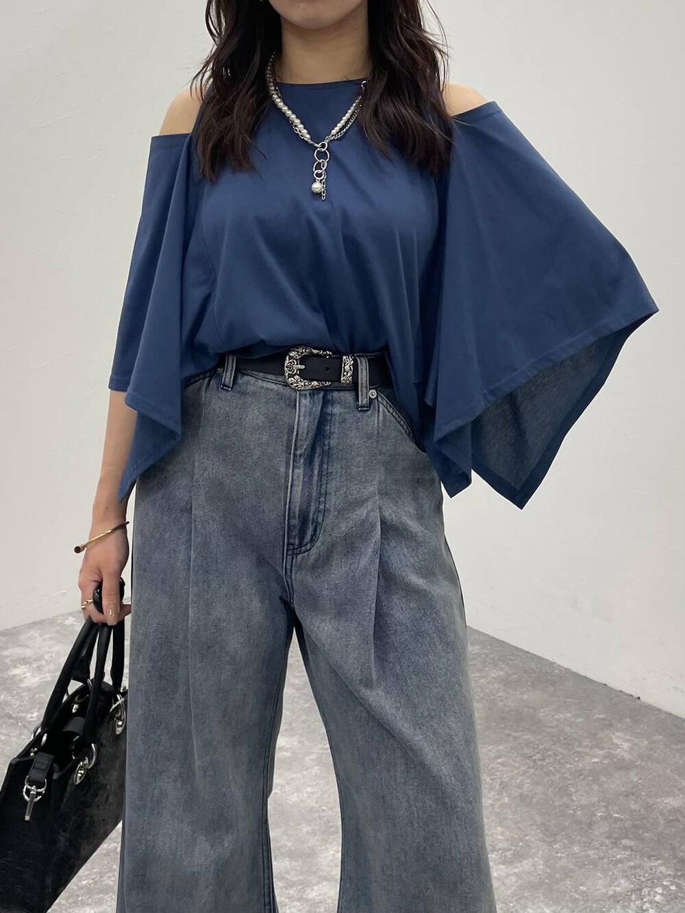 ブルー系のデニムパンツ、ブラック系のショルダーバッグ、ブラック系のサンダルを着用したレディースの夏コーディネートの6枚目の写真