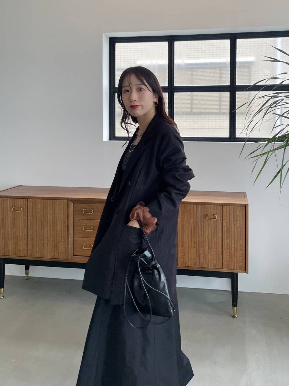 ブラック系のタンクトップ、ブラック系のショルダーバッグ、ブラック系のブーツを着用したレディースの夏コーディネートの5枚目の写真