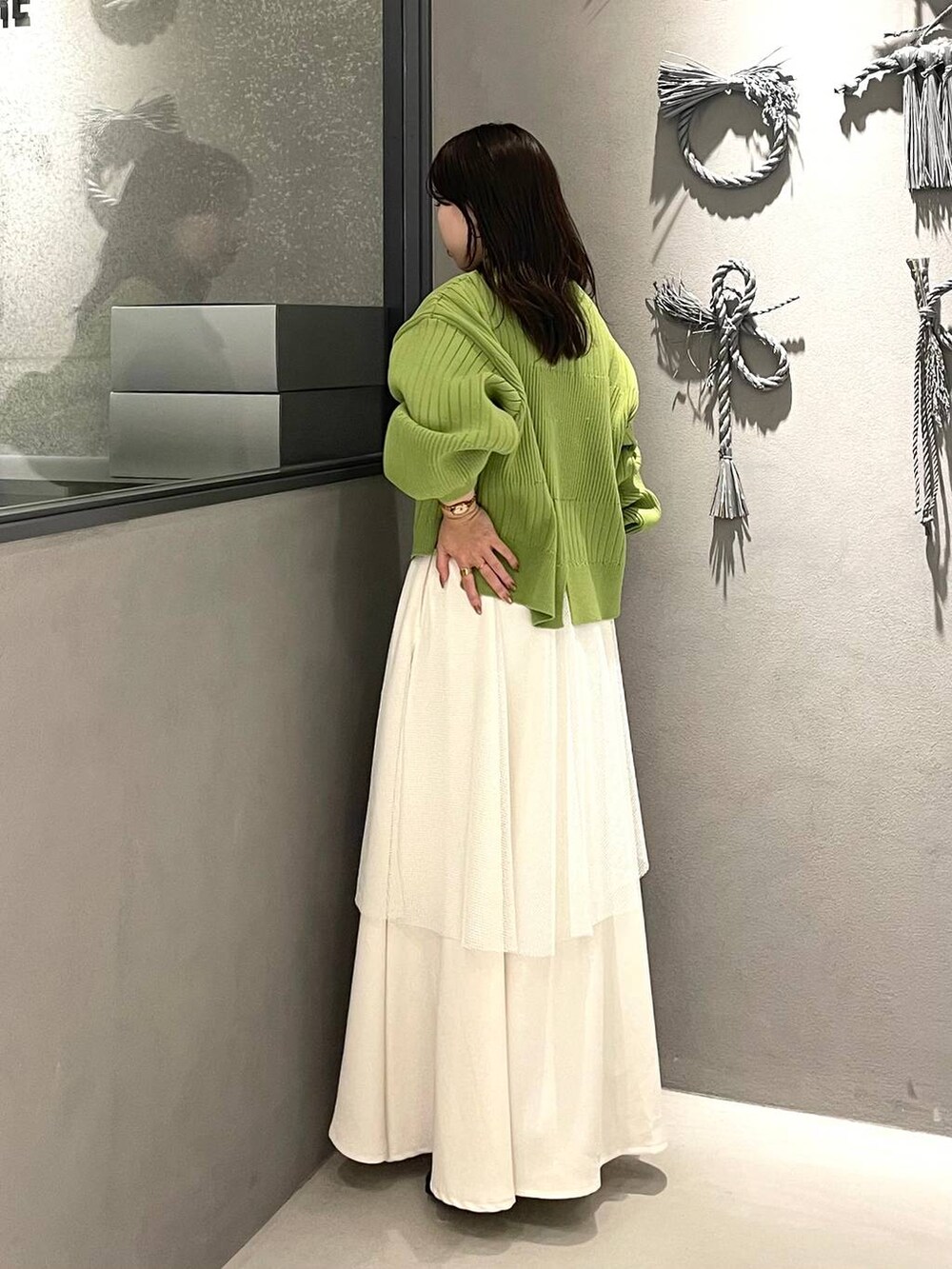 ブラック系のブーツ、イエロー系のニット/セーター、ホワイト系のスカートを着用したレディースの冬コーディネートの2枚目の写真