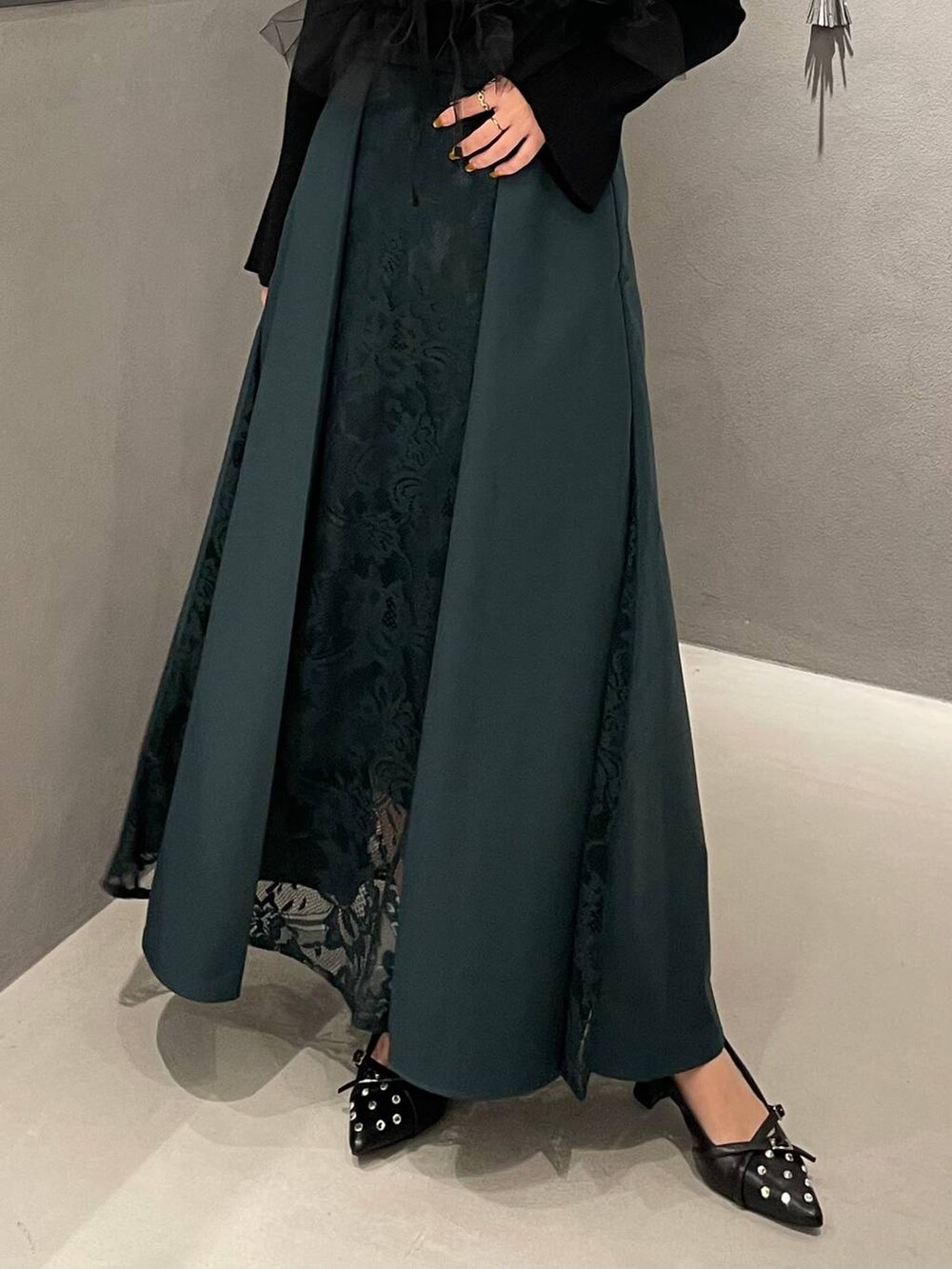 ブラック系のパンプス、ブラック系のニット/セーター、グリーン系のスカートを着用したレディースの夏コーディネートの5枚目の写真