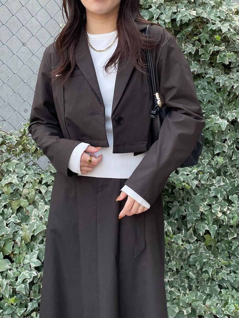 ブラック系のショルダーバッグ、ブラウン系のテーラードジャケット、ブラウン系のスカートを着用したレディースの冬コーディネートの5枚目の写真