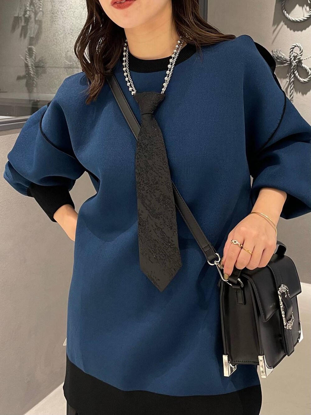 ブラック系のネクタイ、ブラック系のブーツ、ブラック系のショルダーバッグを着用したレディースの秋コーディネートの4枚目の写真