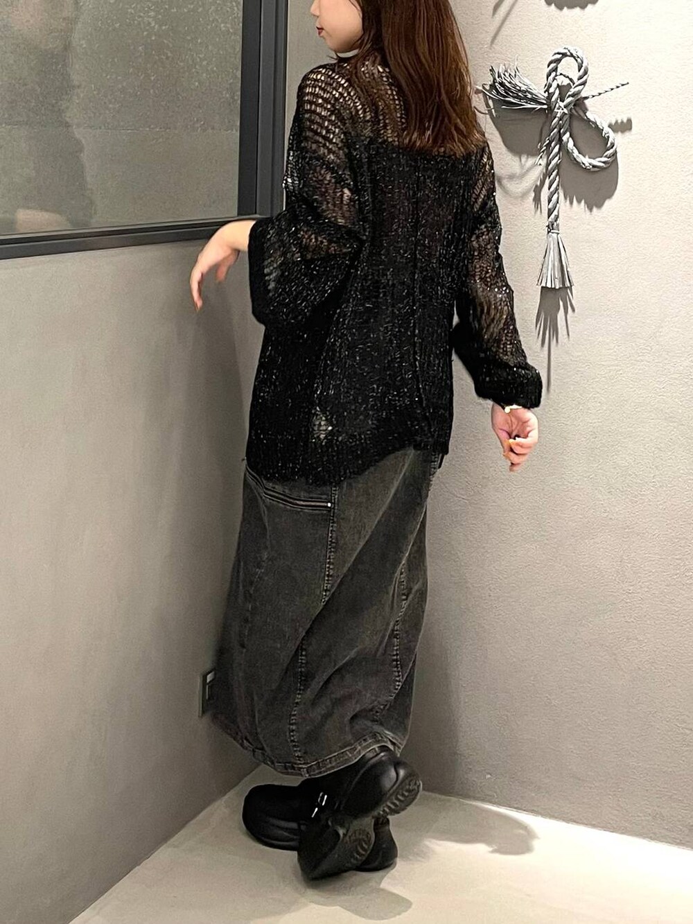 ブラック系のブーツ、ブラック系のニット/セーター、ブラック系のスカートを着用したレディースの夏コーディネートの3枚目の写真