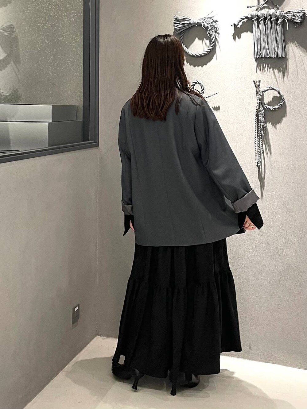 ブラック系のブーツ、グレー系のテーラードジャケット、ブラック系のワンピースを着用したレディースの冬コーディネートの3枚目の写真