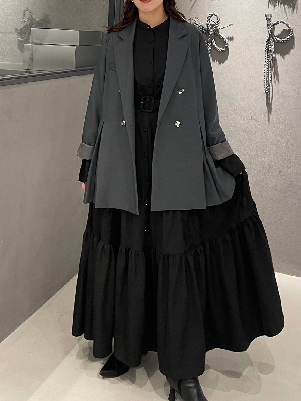 ブラック系のブーツ、グレー系のテーラードジャケット、ブラック系のワンピースを着用したレディースの冬コーディネートの4枚目の写真