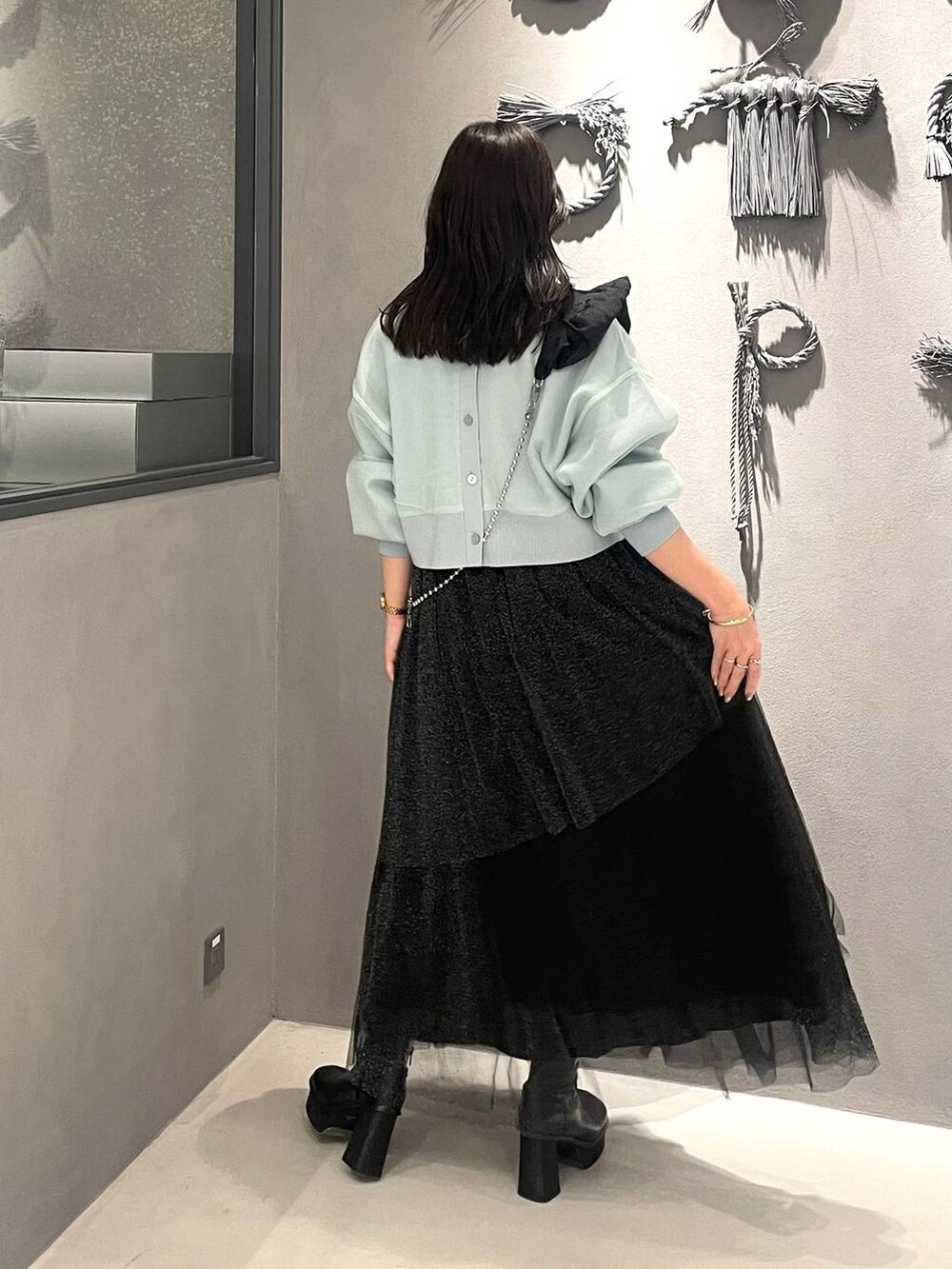 ブラック系のブーツ、グリーン系のカーディガン/ボレロ、ブラック系のスカートを着用したレディースの冬コーディネートの3枚目の写真