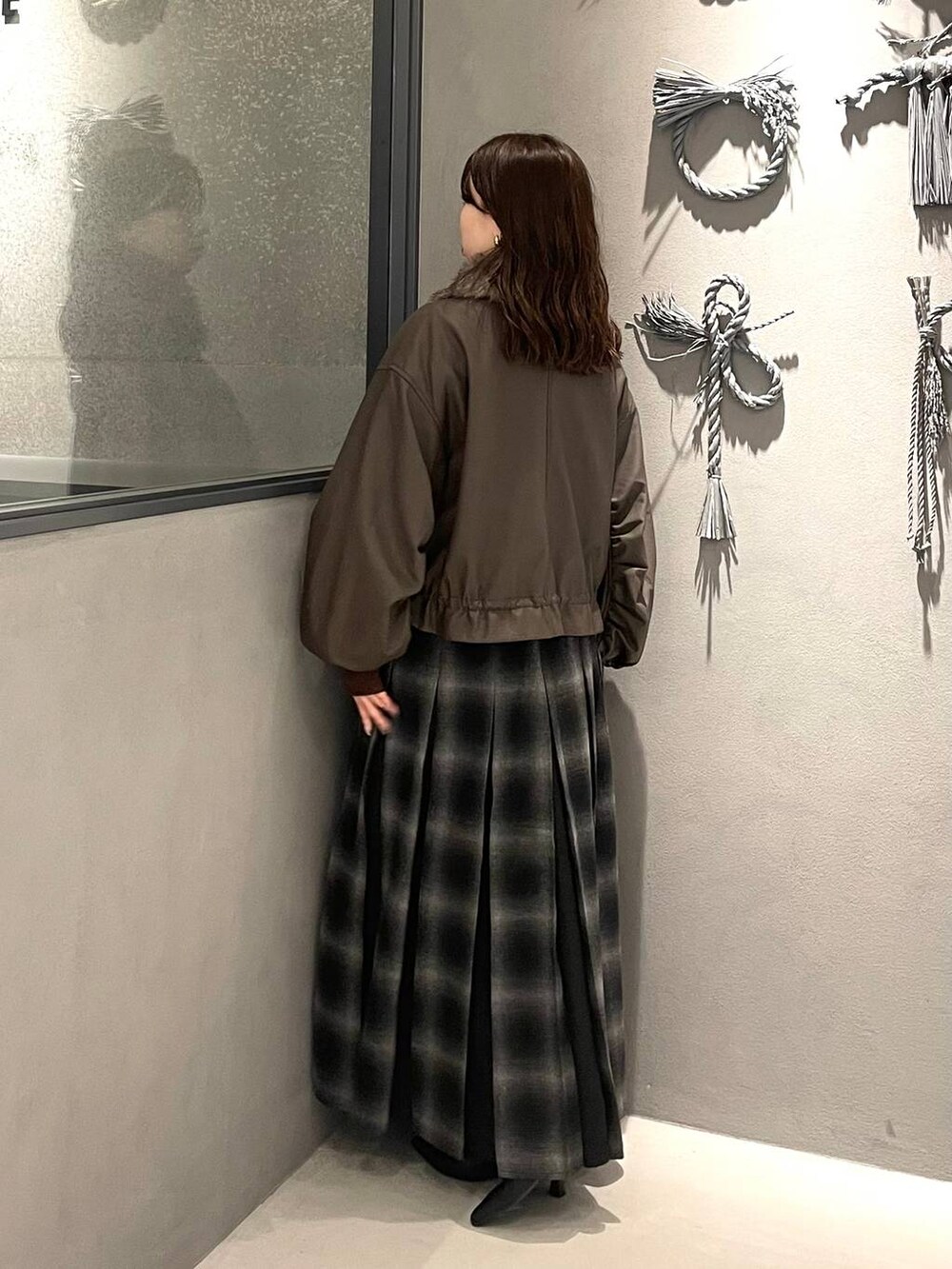 レッド系のニット/セーター、ブラック系のブーツ、ブラウン系のブルゾンを着用したレディースの秋コーディネートの2枚目の写真