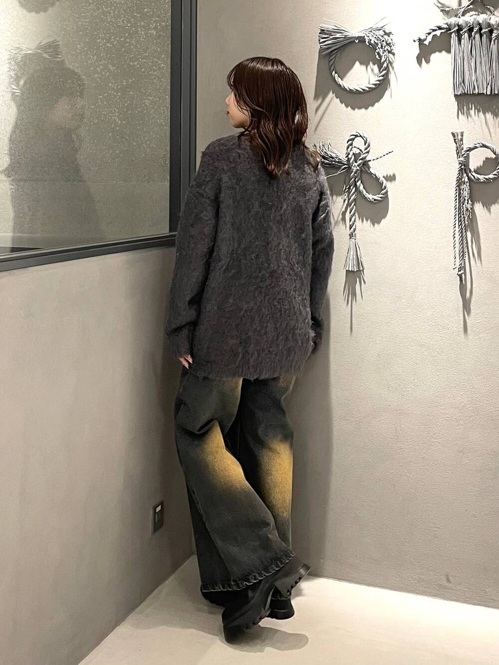 オレンジ系のデニムパンツ、ブラック系のブーツ、グレー系のカーディガン/ボレロを着用したレディースの秋コーディネートの2枚目の写真