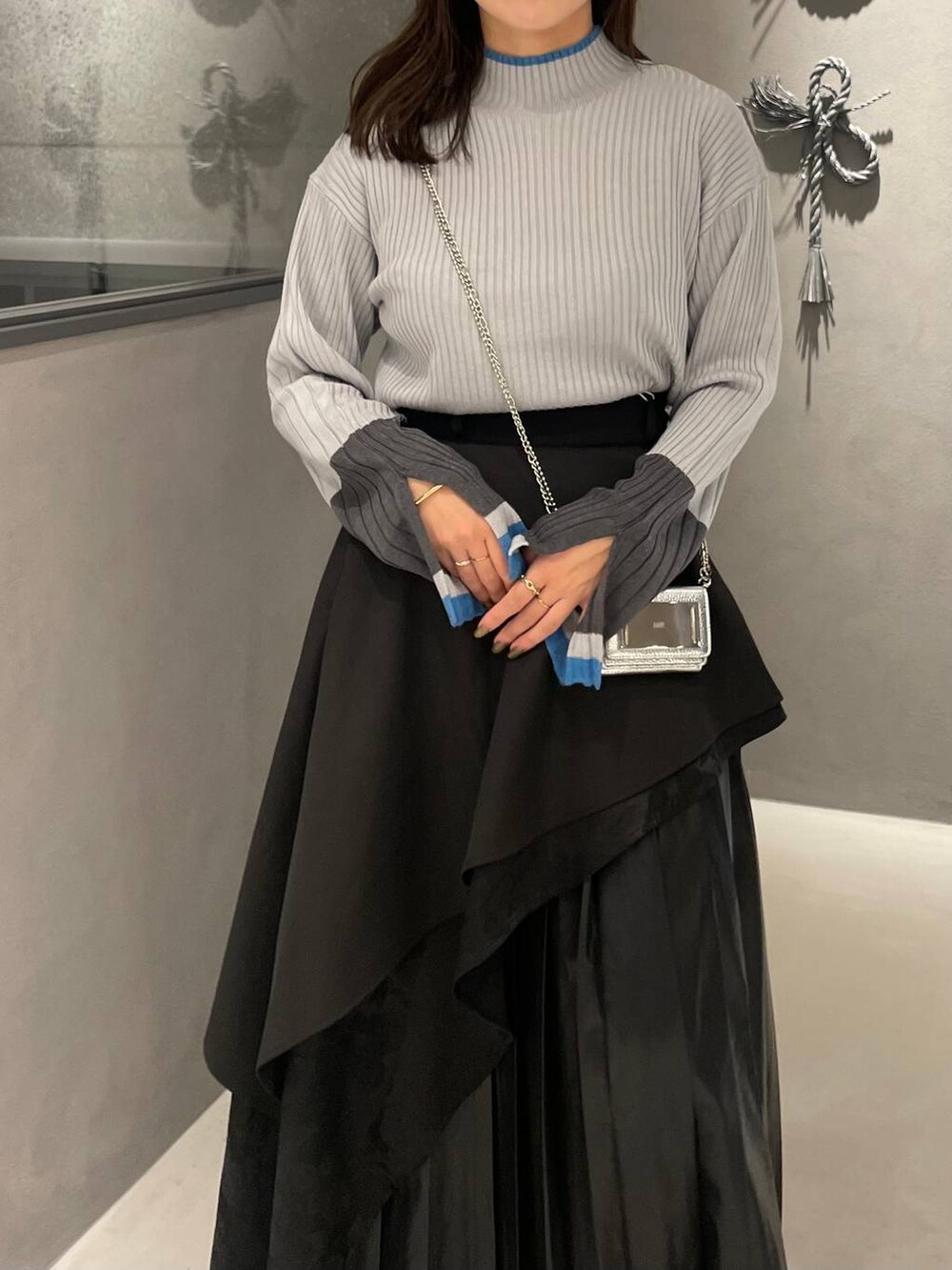 ブラック系のスカート、ブラック系のパンプス、グレー系のニット/セーターを着用したレディースの秋コーディネートの4枚目の写真