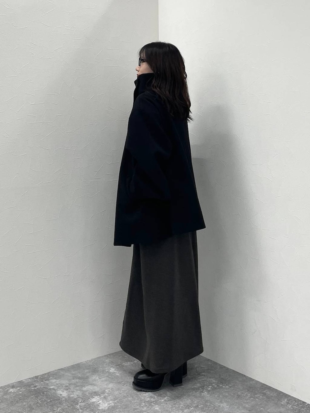 ブラック系のチェスターコート、グレー系のニット/セーター、ブラック系のブーツを着用したレディースの秋コーディネートの6枚目の写真