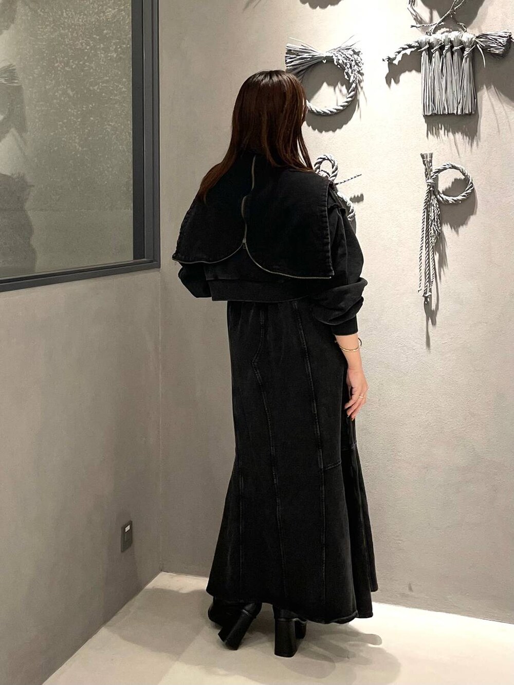 ブラック系のタンクトップ、ブラック系のブーツ、ブラック系のスカートを着用したレディースの秋コーディネートの3枚目の写真