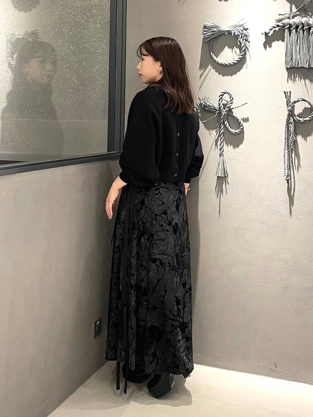 ブラック系のブーツ、ブラック系のニット/セーター、ブラック系のスカートを着用したレディースの冬コーディネートの2枚目の写真