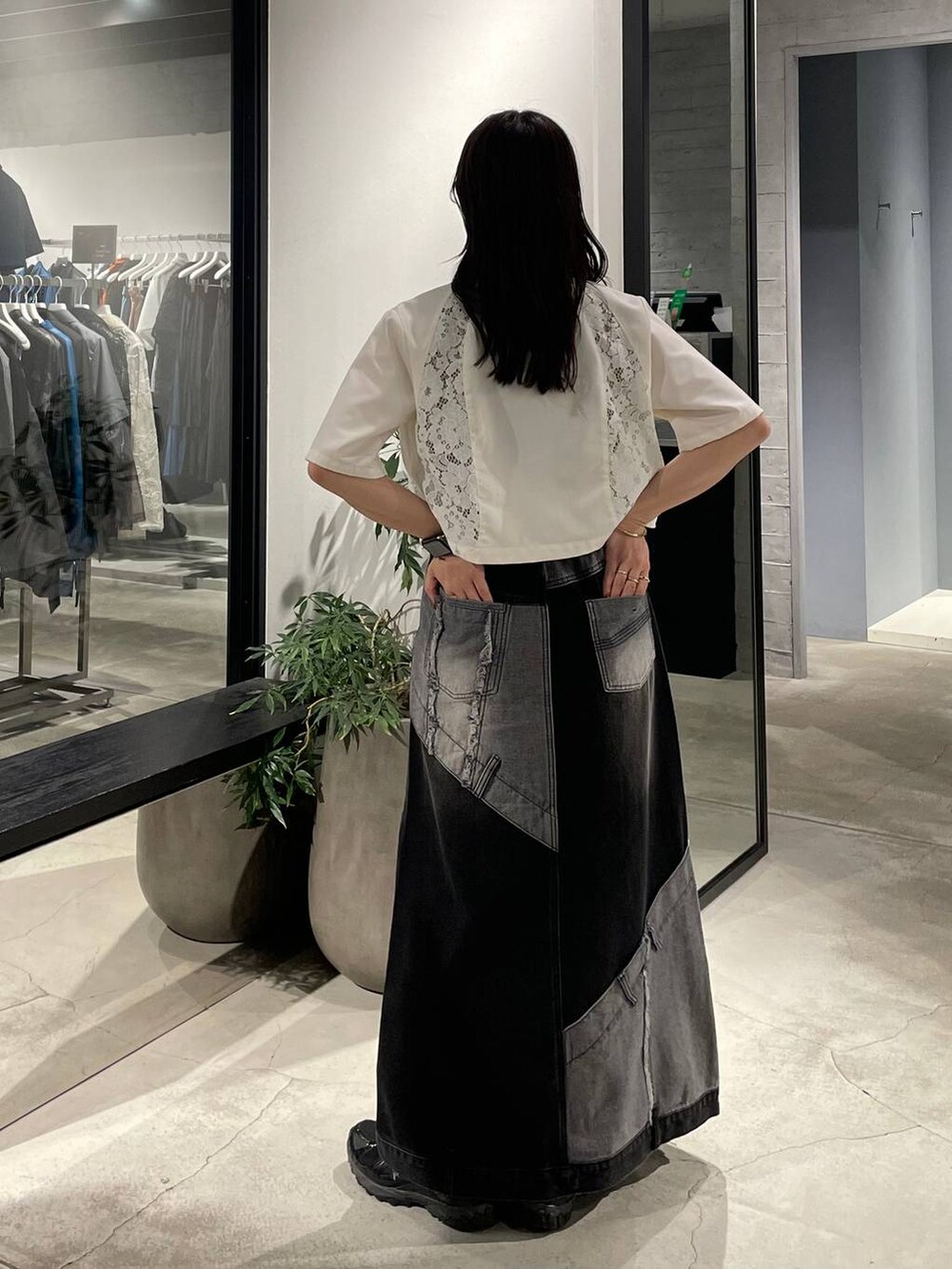 イエロー系のタンクトップ、ブラック系のデニムスカート、ホワイト系のテーラードジャケットを着用したレディースの春コーディネートの3枚目の写真