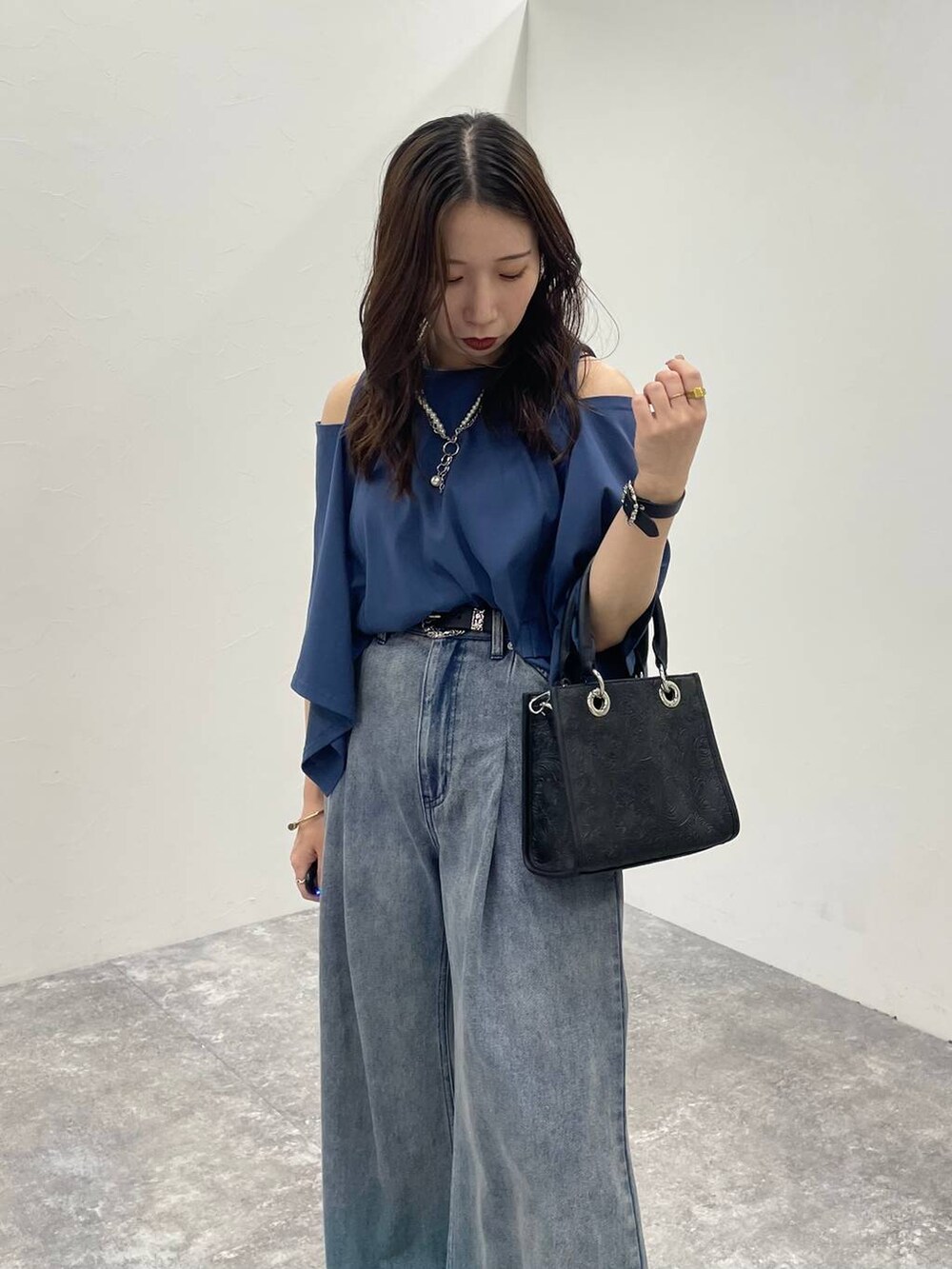 ブルー系のデニムパンツ、ブラック系のショルダーバッグ、ブラック系のサンダルを着用したレディースの夏コーディネートの4枚目の写真