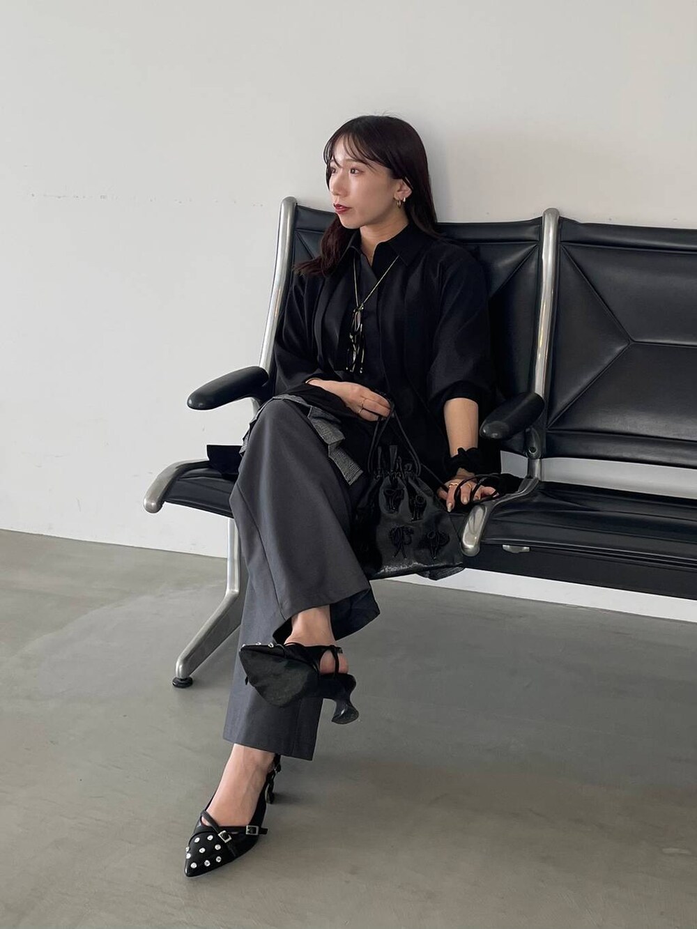 ブラック系のパンプス、ブラック系のショルダーバッグ、ブラック系のシャツ/ブラウスを着用したレディースの夏コーディネートの2枚目の写真