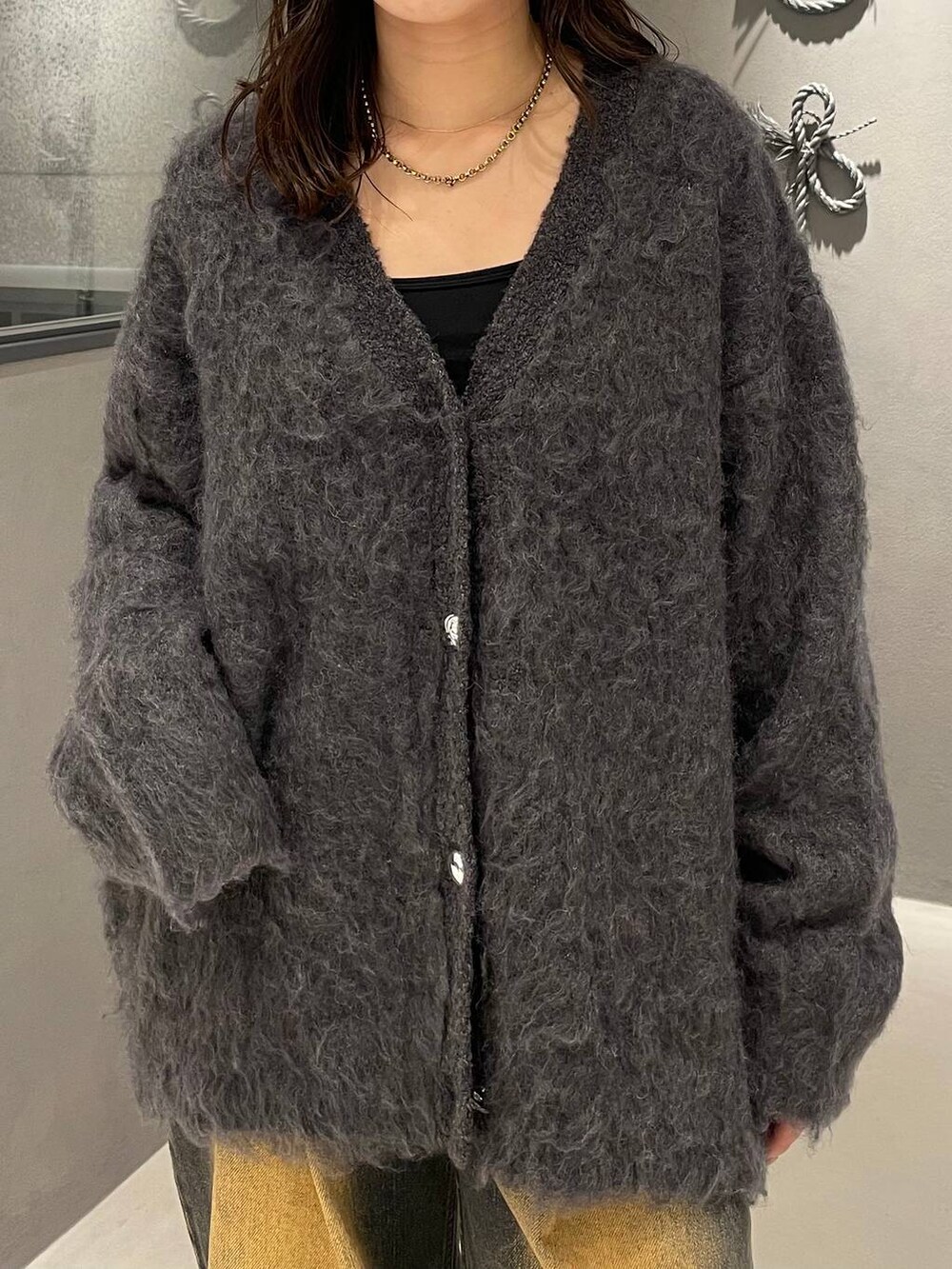 オレンジ系のデニムパンツ、ブラック系のブーツ、グレー系のカーディガン/ボレロを着用したレディースの秋コーディネートの4枚目の写真