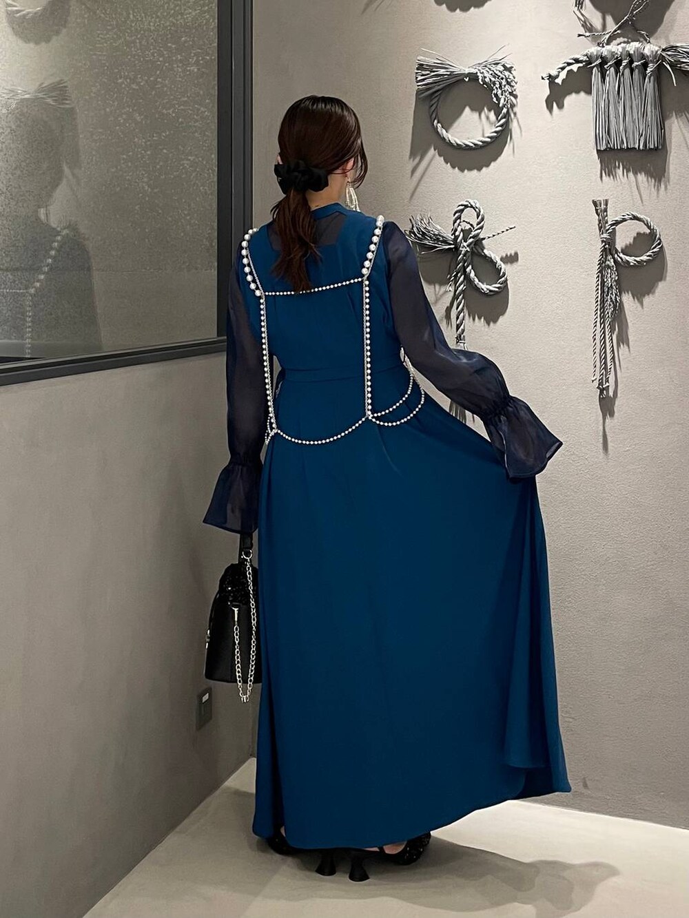 ブラック系のパンプス、ブラック系のショルダーバッグ、ホワイト系のサスペンダーを着用したレディースの秋コーディネートの2枚目の写真