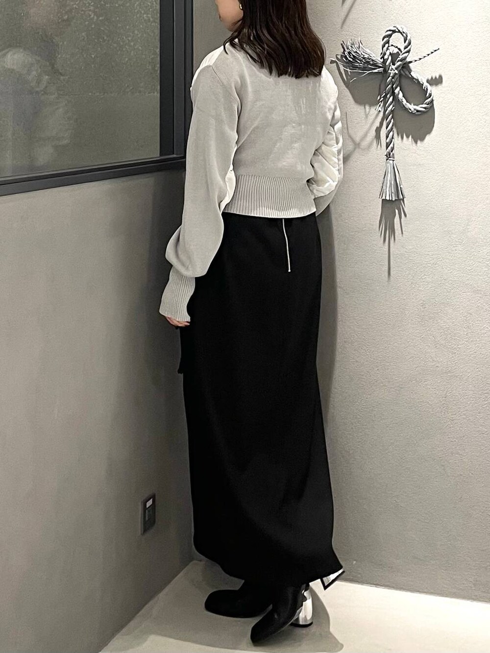 ブラック系のブーツ、ブラック系のスカート、グレー系のニット/セーターを着用したレディースの秋コーディネートの4枚目の写真