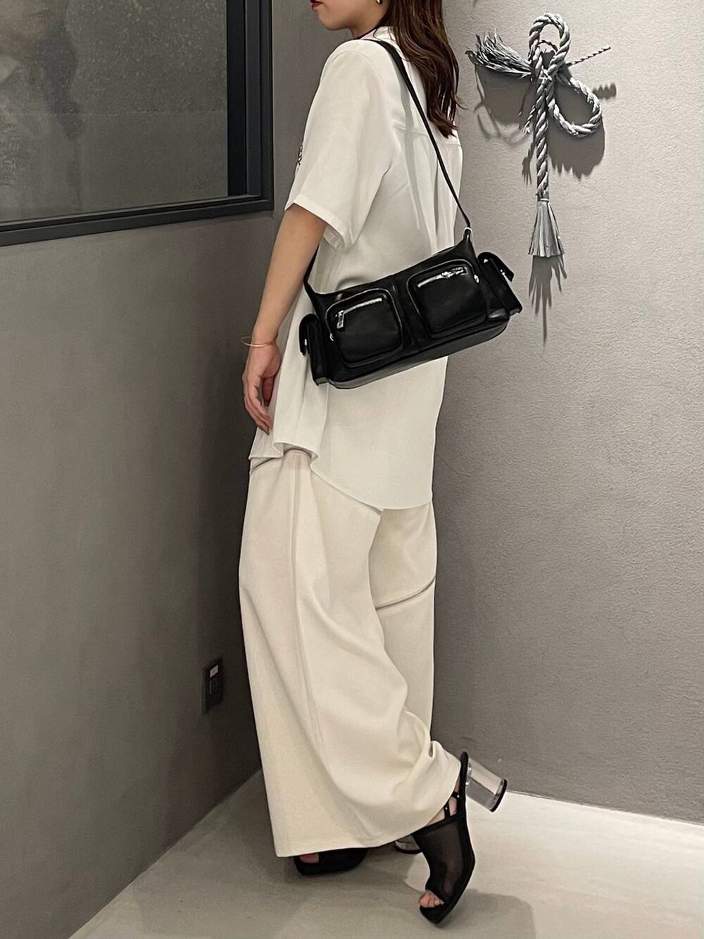 ブラック系のサンダル、ホワイト系のシャツ/ブラウス、ブラック系のショルダーバッグを着用したレディースの夏コーディネートの3枚目の写真