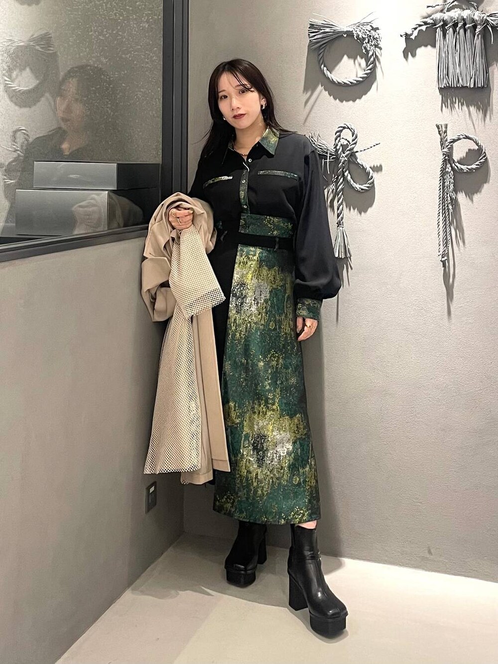 イエロー系のスカート、ブラック系のブーツ、ホワイト系のトレンチコートを着用したレディースの冬コーディネートの2枚目の写真