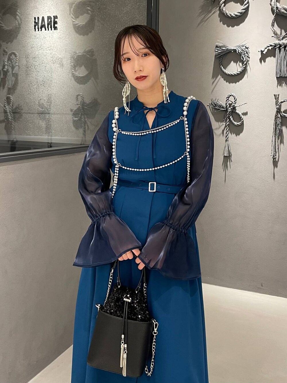 ブラック系のパンプス、ブラック系のショルダーバッグ、ホワイト系のサスペンダーを着用したレディースの秋コーディネートの4枚目の写真