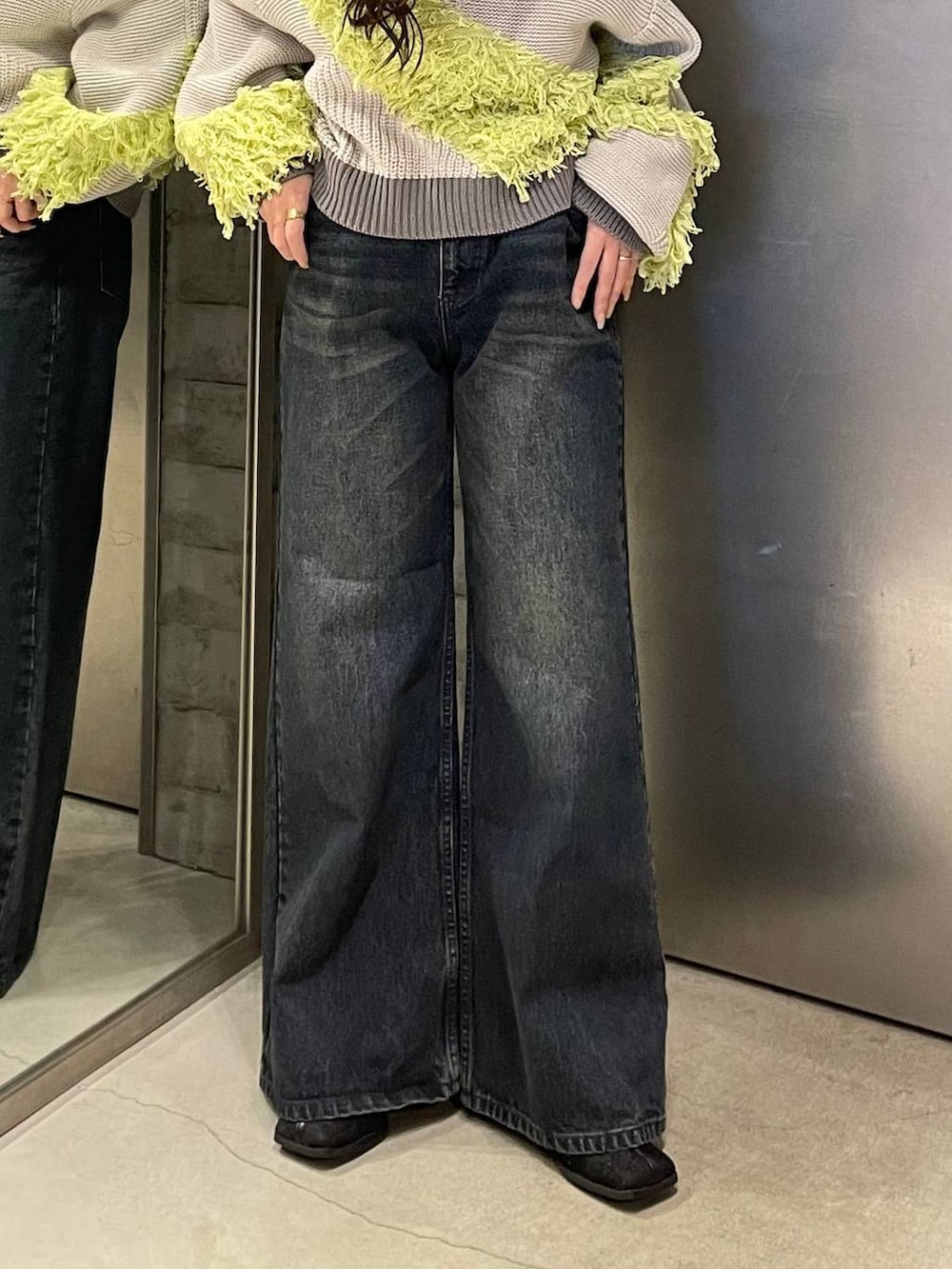 ブルー系のデニムパンツ、ブラック系のブーツ、イエロー系のニット/セーターを着用したレディースの冬コーディネートの5枚目の写真