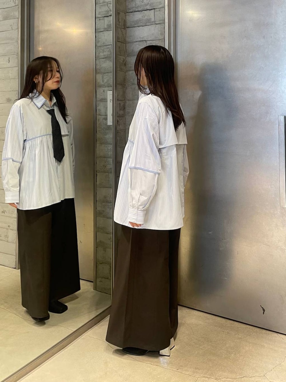 ブラック系のネクタイ、ブラック系のブーツ、ブルー系のシャツ/ブラウスを着用したレディースの春コーディネートの2枚目の写真