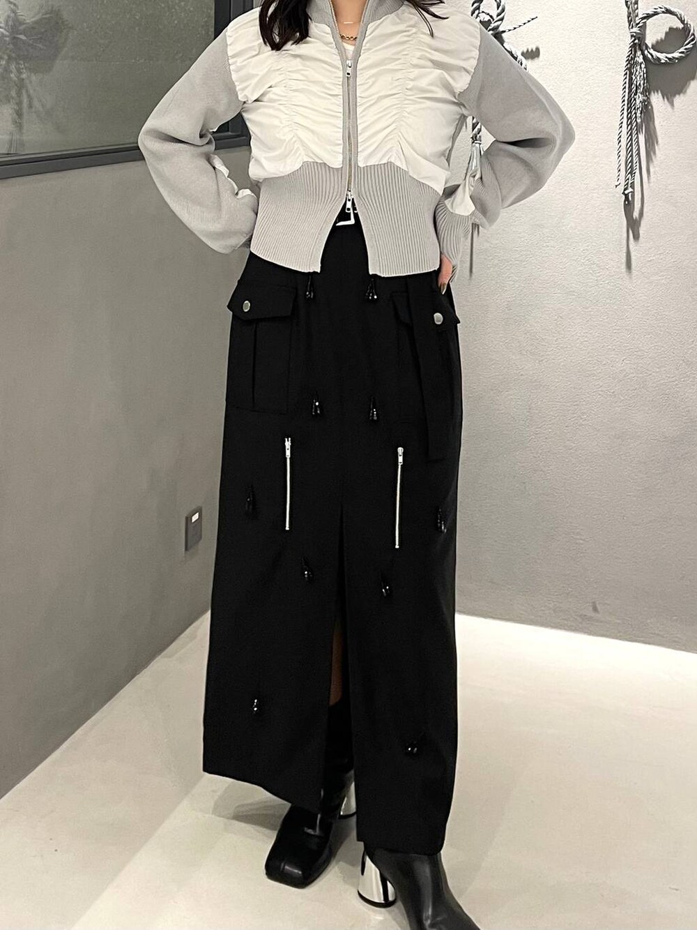 ブラック系のブーツ、ブラック系のスカート、グレー系のニット/セーターを着用したレディースの秋コーディネートの3枚目の写真