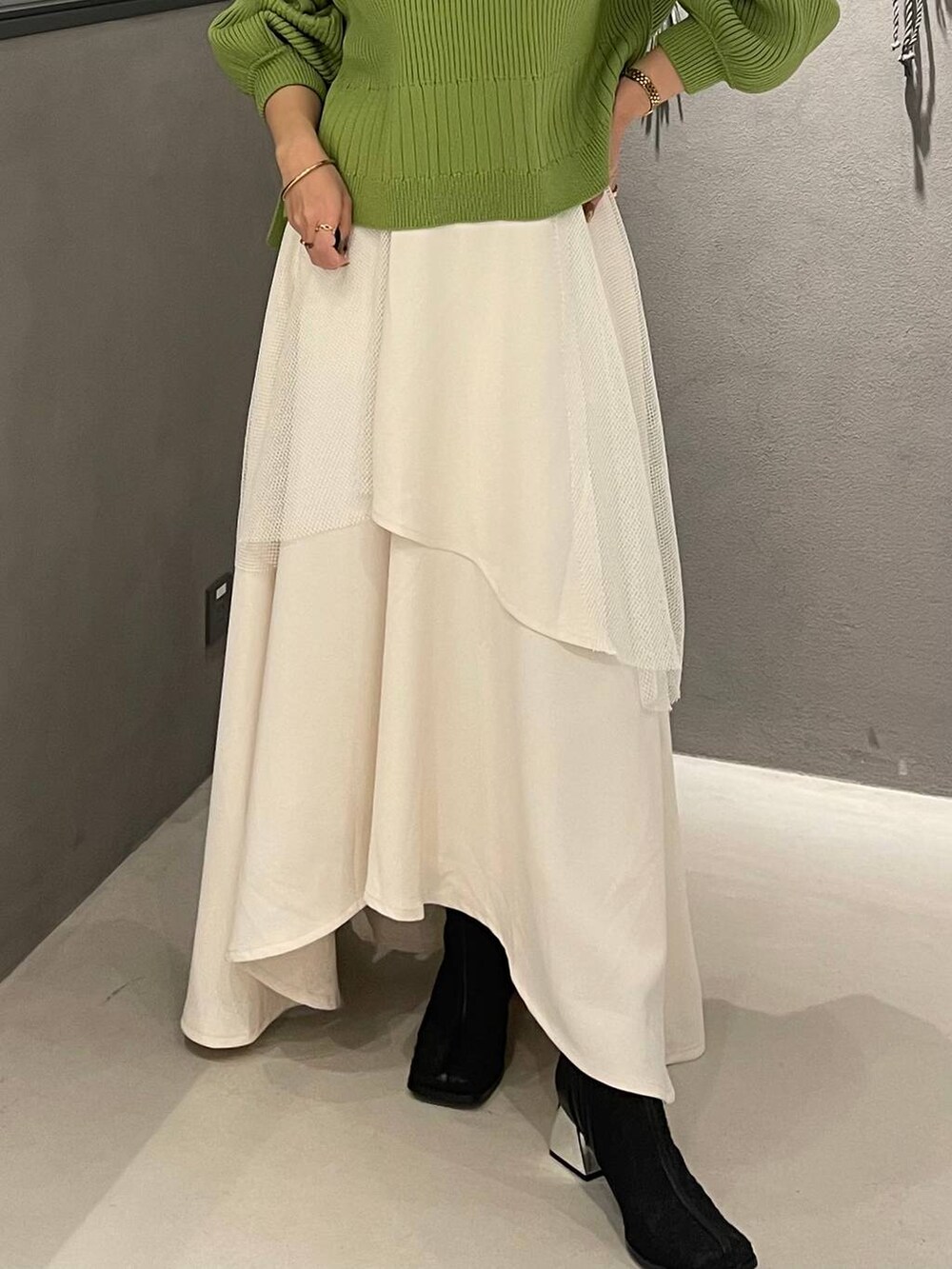 ブラック系のブーツ、イエロー系のニット/セーター、ホワイト系のスカートを着用したレディースの冬コーディネートの5枚目の写真