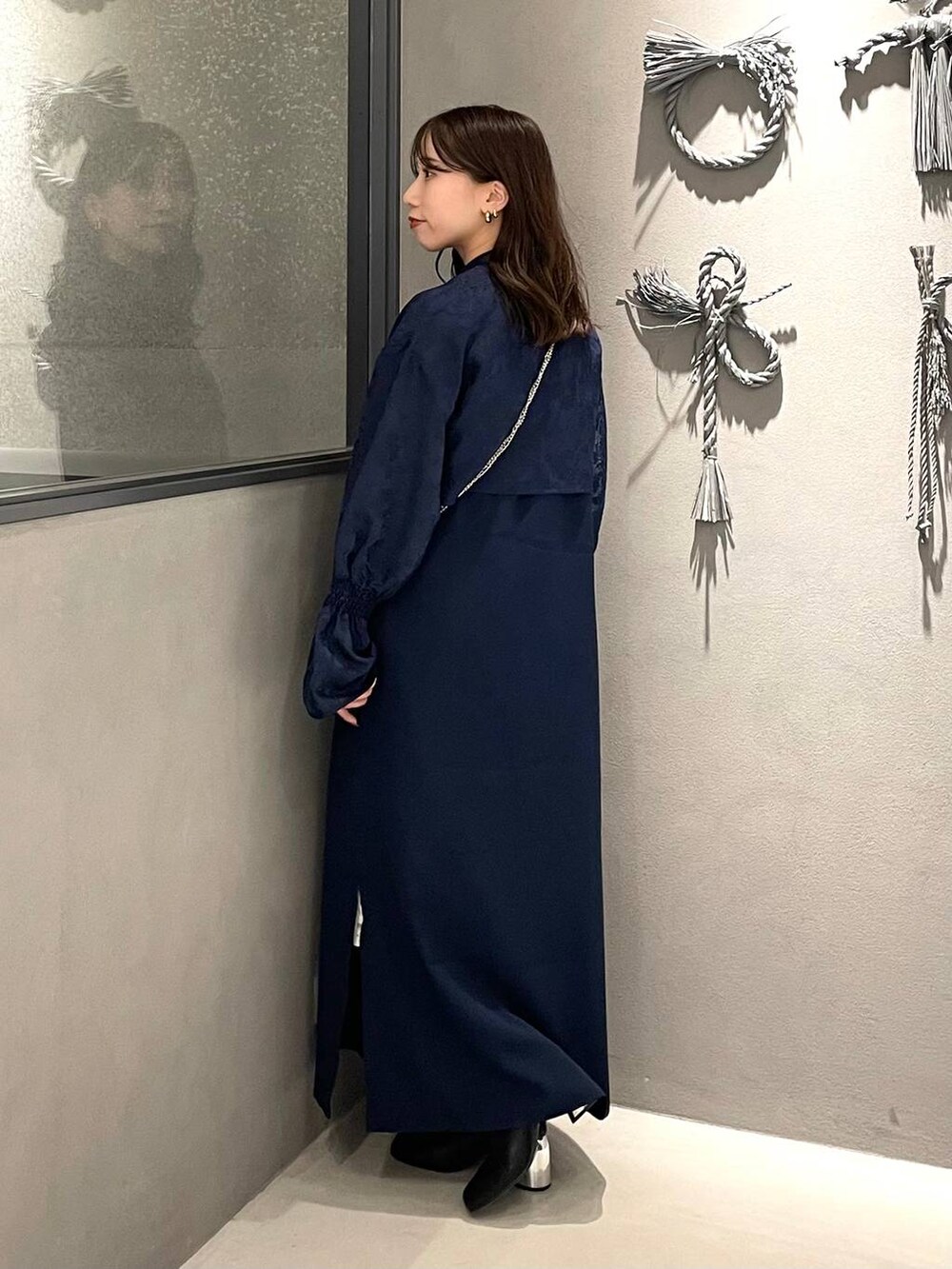 ブラック系のブーツ、ブルー系のワンピース、ブラック系の財布を着用したレディースの秋コーディネートの2枚目の写真