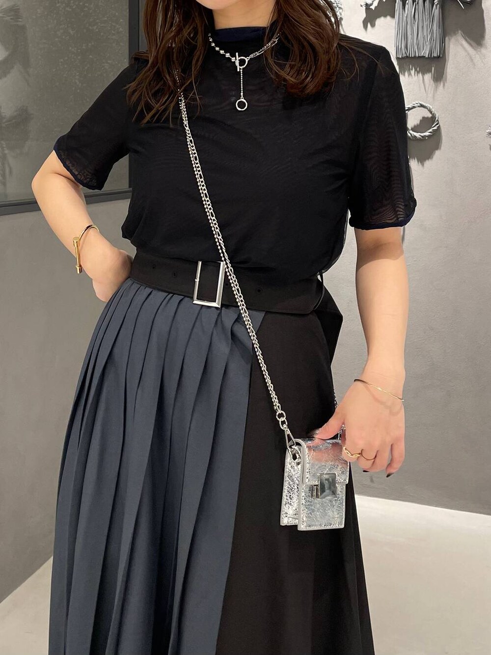 ブラック系のサンダル、グレー系のスカート、シルバー系のショルダーバッグを着用したレディースの春コーディネートの4枚目の写真