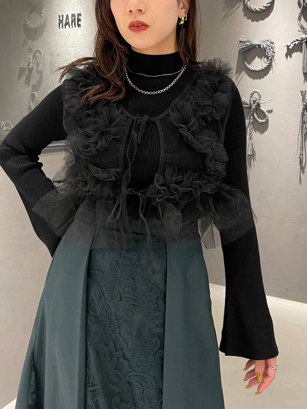 ブラック系のパンプス、ブラック系のニット/セーター、グリーン系のスカートを着用したレディースの夏コーディネートの4枚目の写真