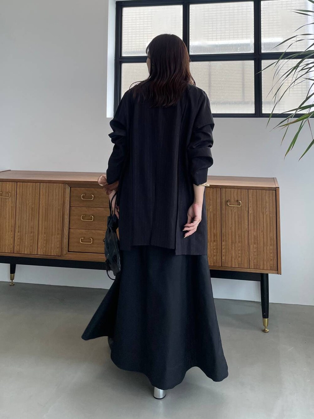 ブラック系のタンクトップ、ブラック系のショルダーバッグ、ブラック系のブーツを着用したレディースの夏コーディネートの3枚目の写真