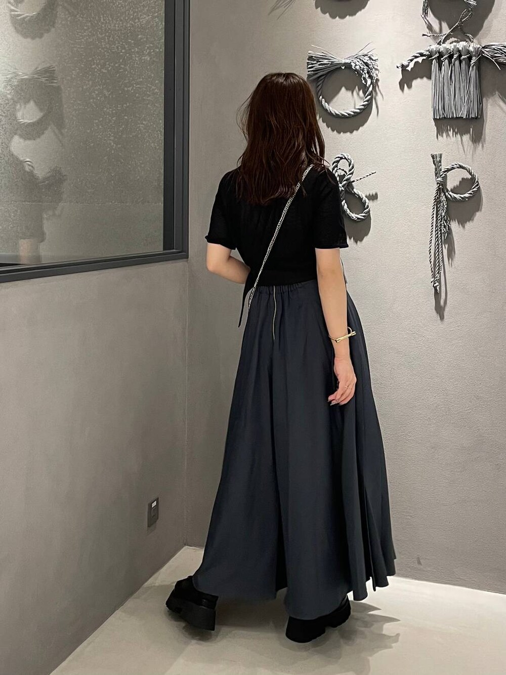 ブラック系のサンダル、グレー系のスカート、シルバー系のショルダーバッグを着用したレディースの春コーディネートの3枚目の写真