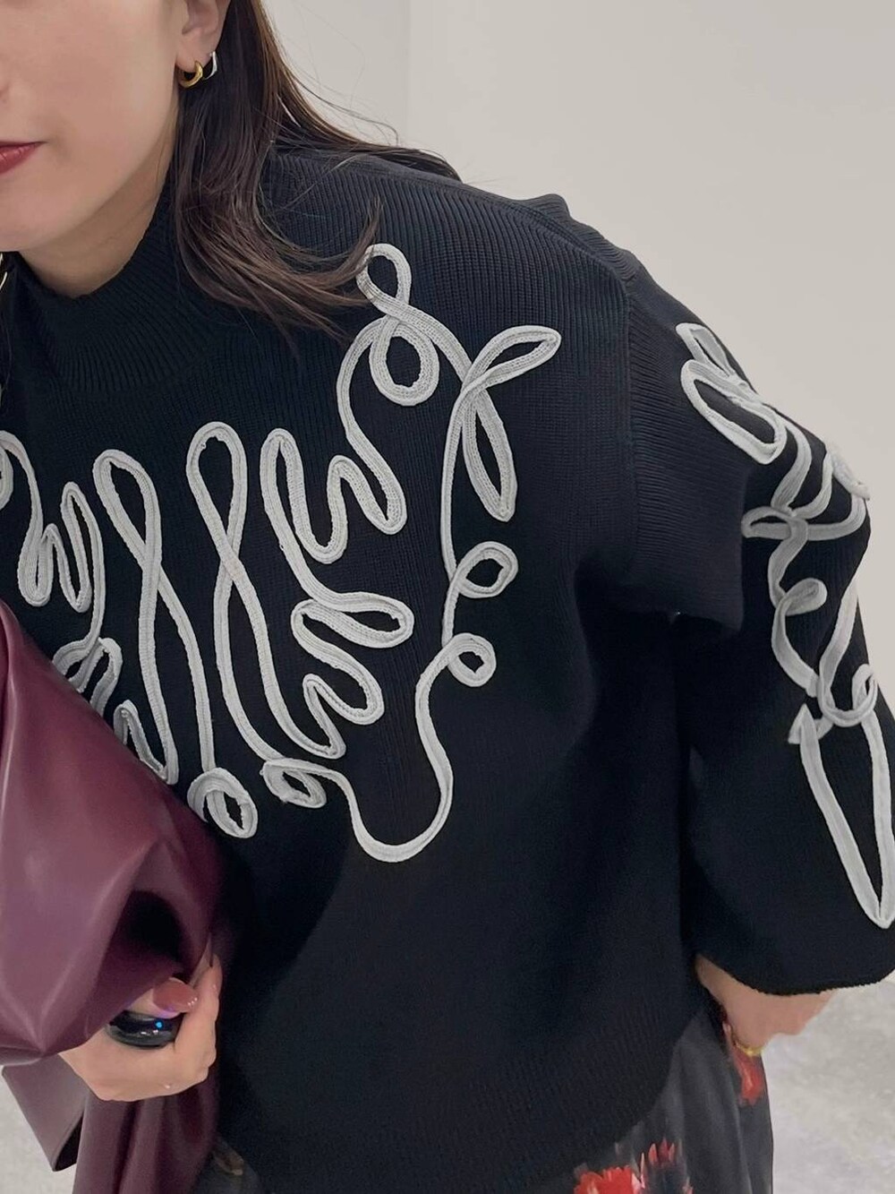 レッド系のトートバッグ、ブラック系のブーツ、ブラック系のニット/セーターを着用したレディースの夏コーディネートの5枚目の写真