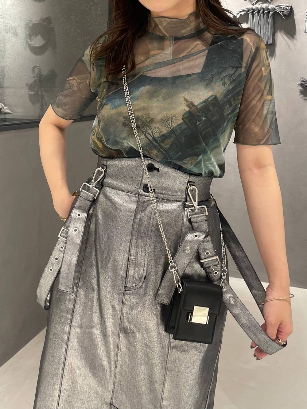 ブラック系のサンダル、シルバー系のスカート、ブラック系のショルダーバッグを着用したレディースの春コーディネートの3枚目の写真