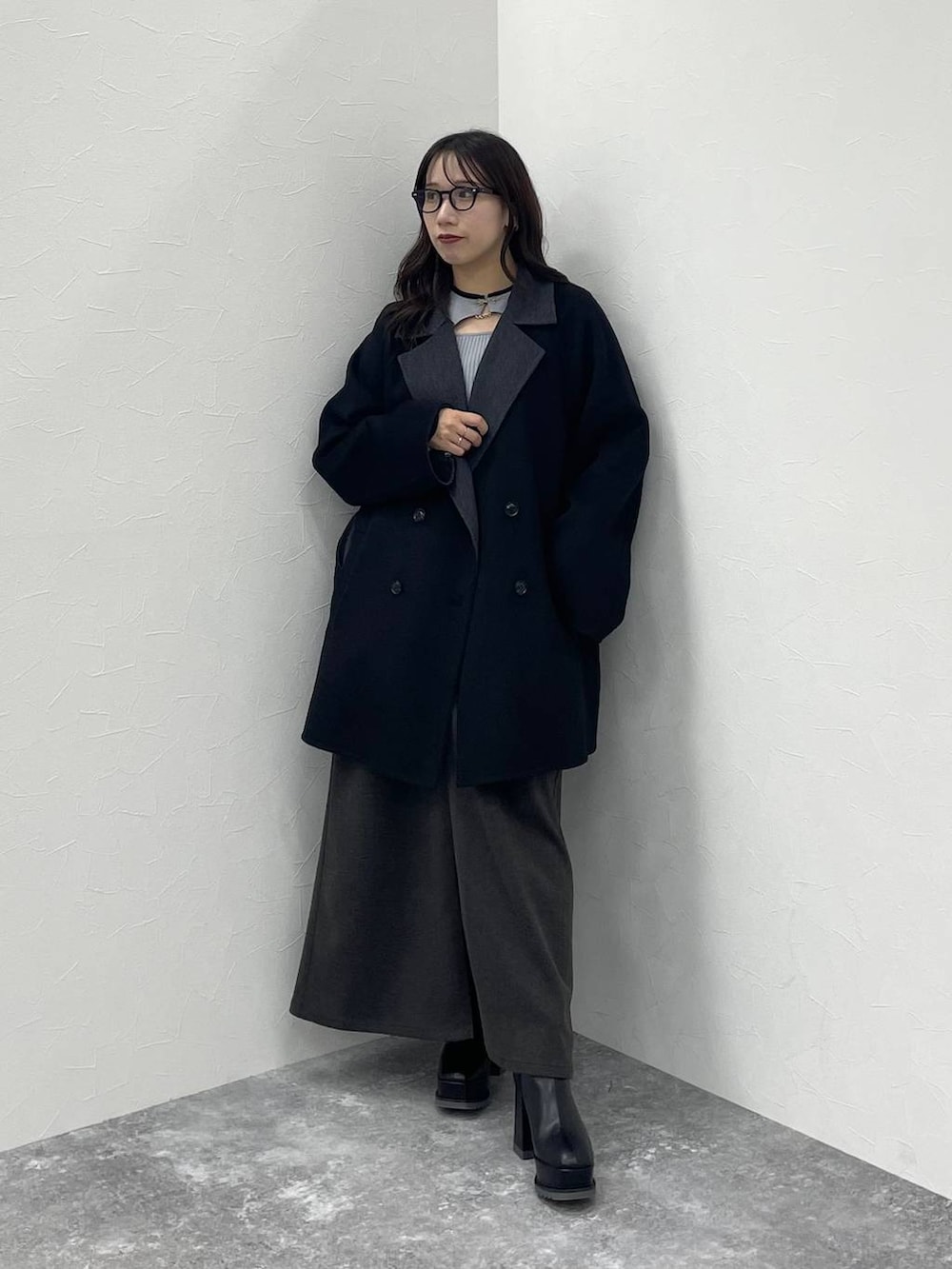 グレー系のニット/セーター、ブラック系のチェスターコート、ブラック系のブーツを着用したレディースの秋コーディネートの2枚目の写真