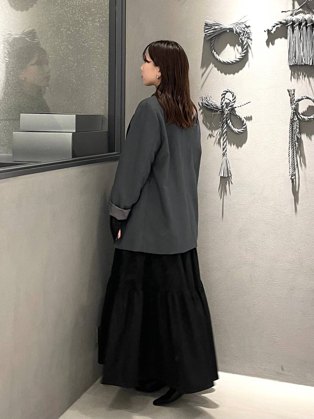 ブラック系のブーツ、グレー系のテーラードジャケット、ブラック系のワンピースを着用したレディースの冬コーディネートの2枚目の写真