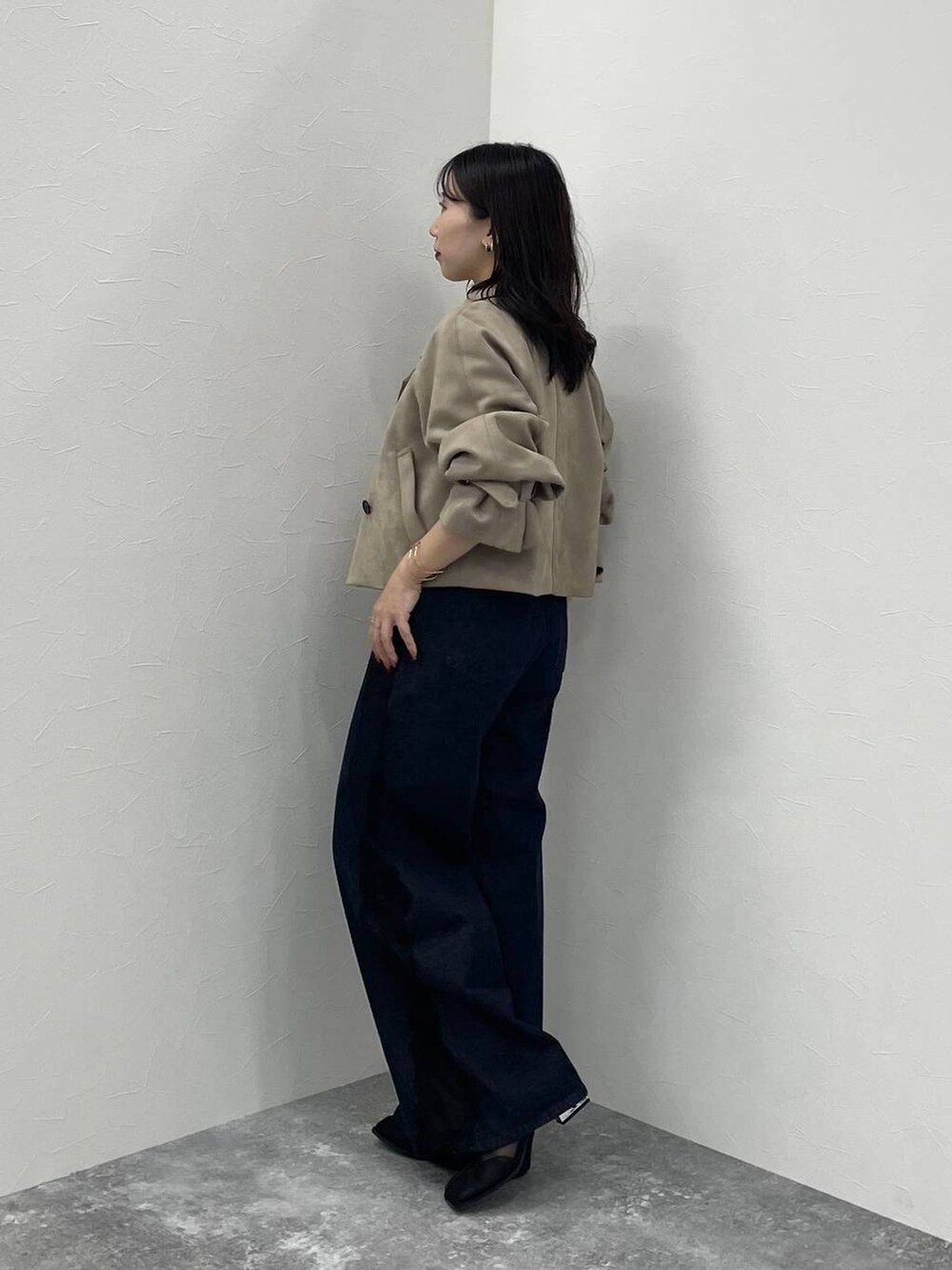 ブルー系のデニムパンツ、ブラック系のブーツ、ベージュ系のトレンチコートを着用したレディースの夏コーディネートの2枚目の写真