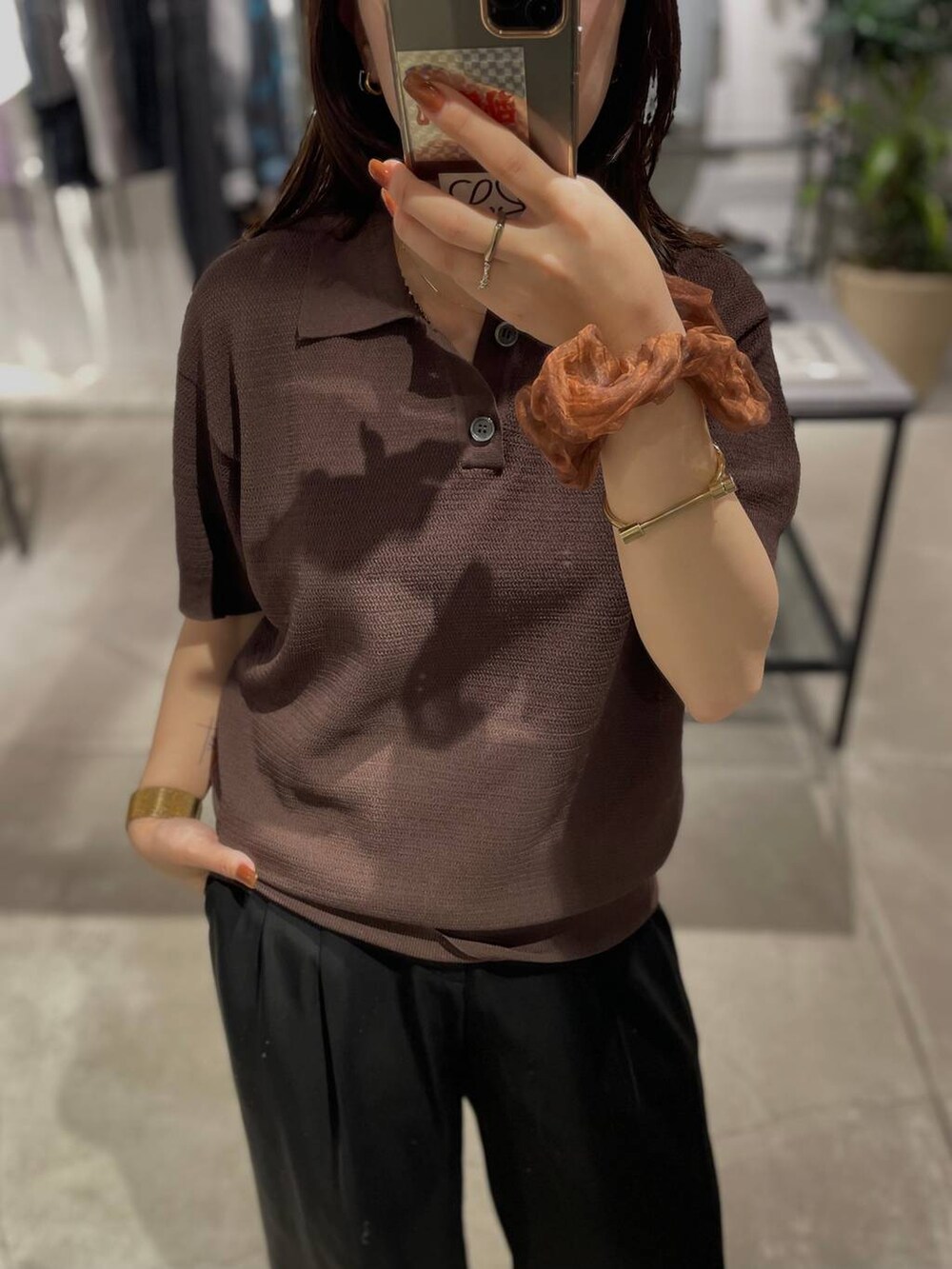 ブラウン系のポロシャツを着用したレディースの夏コーディネートの2枚目の写真