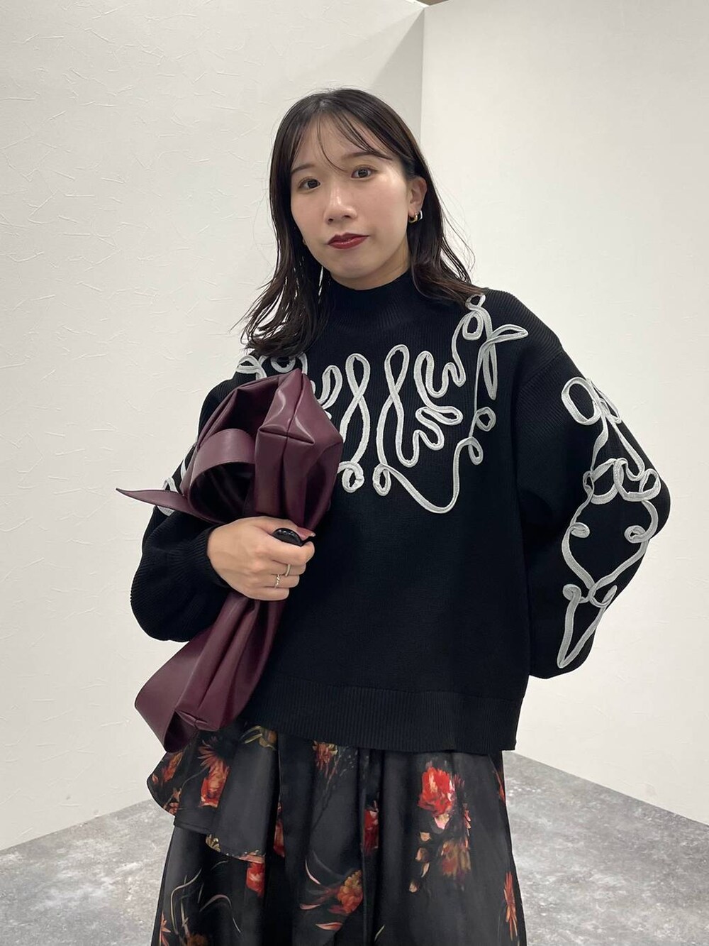 レッド系のトートバッグ、ブラック系のブーツ、ブラック系のニット/セーターを着用したレディースの夏コーディネートの4枚目の写真