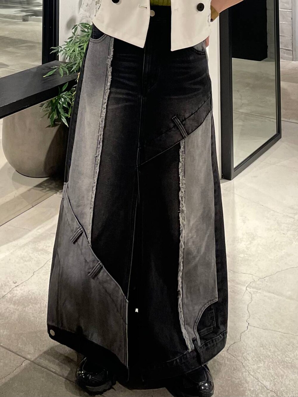 イエロー系のタンクトップ、ブラック系のデニムスカート、ホワイト系のテーラードジャケットを着用したレディースの春コーディネートの5枚目の写真