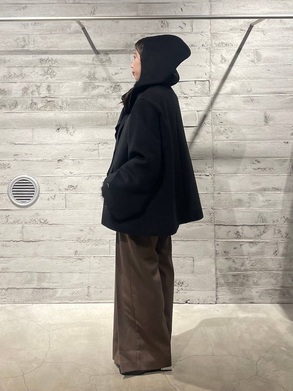 ブラック系のブーツ、ブラック系のノーカラーコート、ブラウン系のその他パンツを着用したレディースの冬コーディネートの3枚目の写真