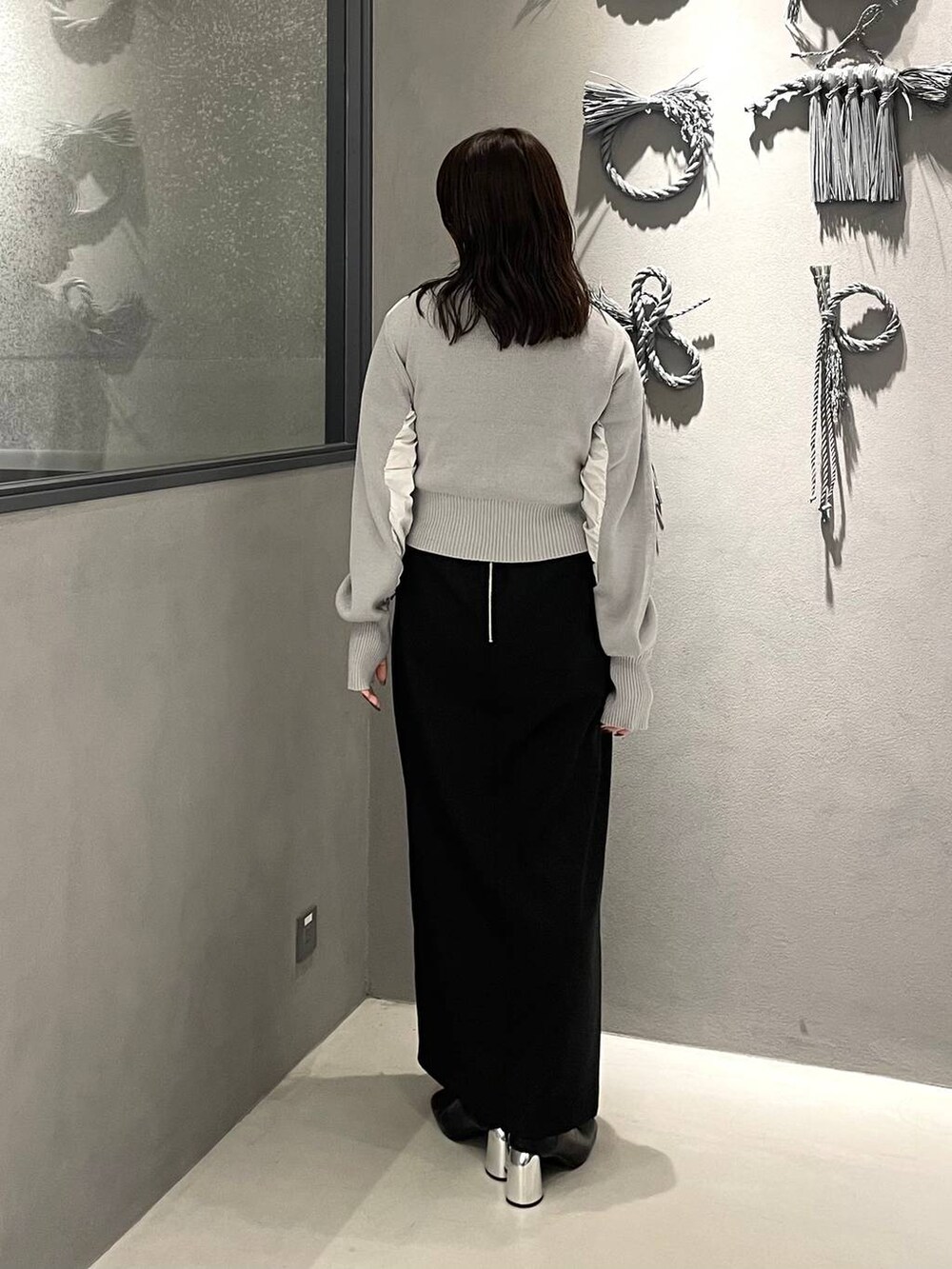 ブラック系のブーツ、ブラック系のスカート、グレー系のニット/セーターを着用したレディースの秋コーディネートの2枚目の写真